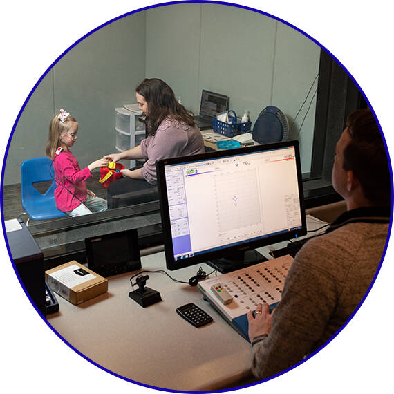 Audiology student with a pediatric Standardized Patient in a hearing booth during an exam.